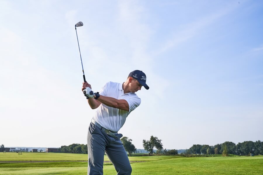 golfer hitting with iron in the golf course