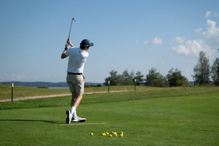 golfer training on course with alignment stick on ground