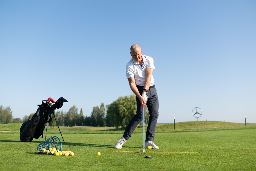 golfer training with alignment sticks and bucket of balls