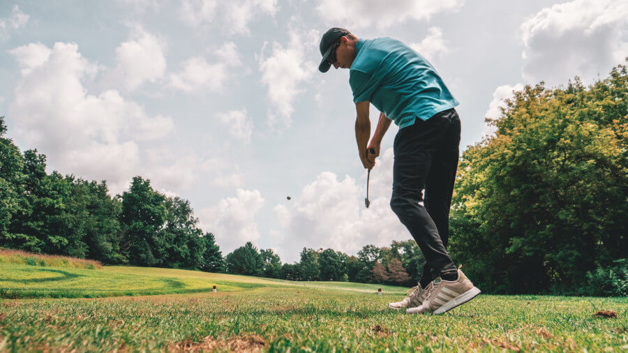 man playing golf on golf course hitting with driver